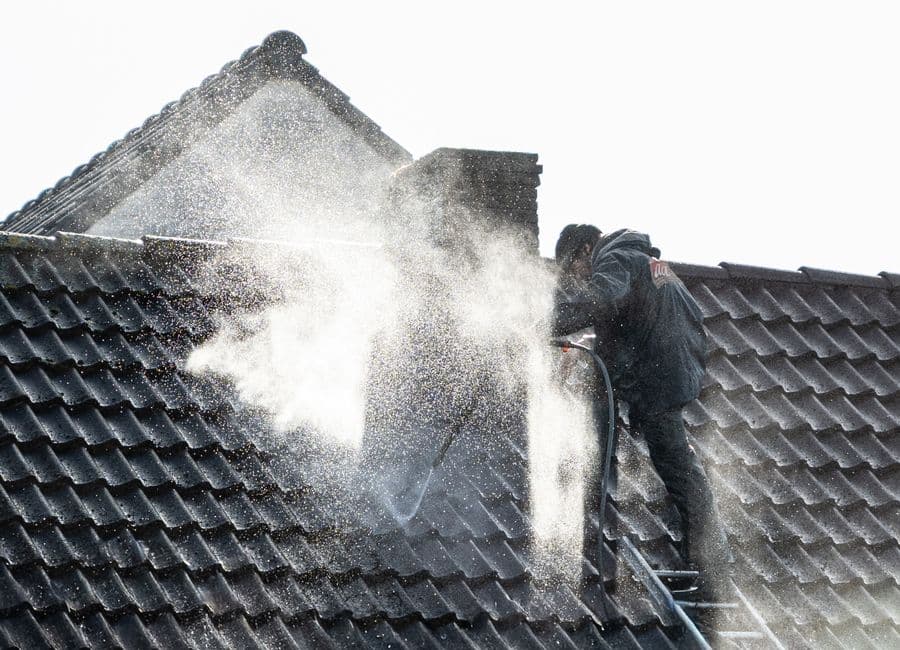 A pro power washing a roof